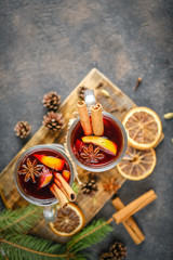 Mulled wine in glasses with apples, orange, cinnamon and star anise. Hot Christmas drink on a dark background top view copy space.