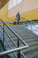 Elegant young man standing on the top of the stairs
