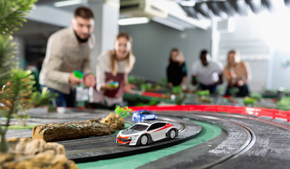 Toy remote control racing cars on the track and enthusiastic players