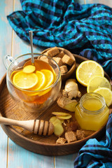 Cup of hot tea with lemon, ginger, honeycomb and honey on a wooden table.