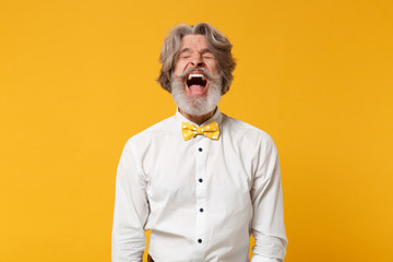 Obraz premium Frustrated elderly gray-haired mustache bearded man in white shirt, bow tie posing isolated on yellow background in studio. People lifestyle concept. Mock up copy space. Screaming keeping eyes closed.