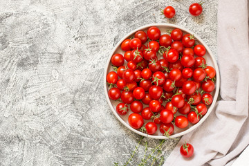 Tiny cherry tomatoes (ciliegini, pachino, cocktail). group of cherry tomatoes on a gray concrete...