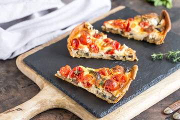 Vegetarian homemade pie, Quiche with cherry tomatoes, eggplant and feta cheese on a dark background