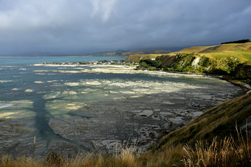 Beautiful New Zealand landscape near Kaikoura, South Bay, with the ocean and landscape under a clouded sky.