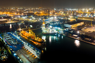 Aerial view of a jack up oil drilling rig and dry dock ship in the shipyard for maintenance during suset time.