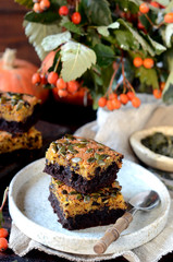Chocolate pumpkin brownie on a plate on a dark wooden background, still life