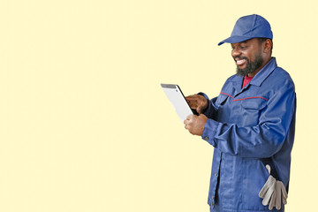 African-American car mechanic with tablet computer on color background