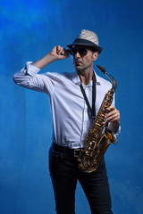 Fototapeta na wymiar Mann mit Altsaxophon vor blauem Hintergrund