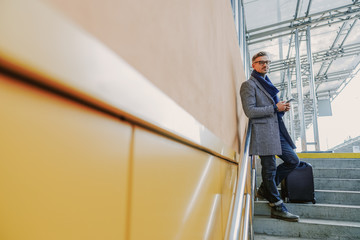 Handsome stylish man with cellphone standing on steps