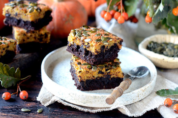 Chocolate pumpkin brownie on a plate on a dark wooden background, still life
