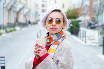 Young woman in sunglasses with a cup of coffee. Lifestyle.