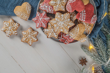 Bright Christmas or New Year wooden background with fir branches, Christmas decorations, Christmas gingerbread cookies, Christmas sweets. Copy space. View from above