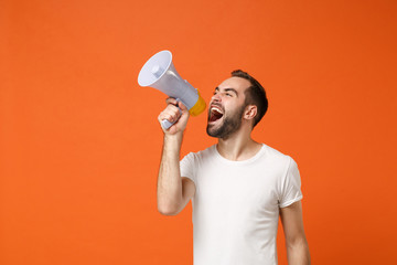 Angry young man in casual white t-shirt posing isolated on bright orange wall background studio...