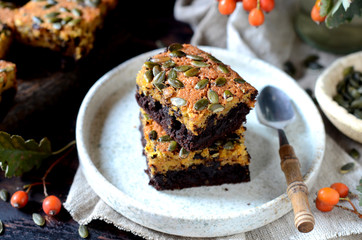 Chocolate pumpkin brownie on a plate on a dark wooden background, still life