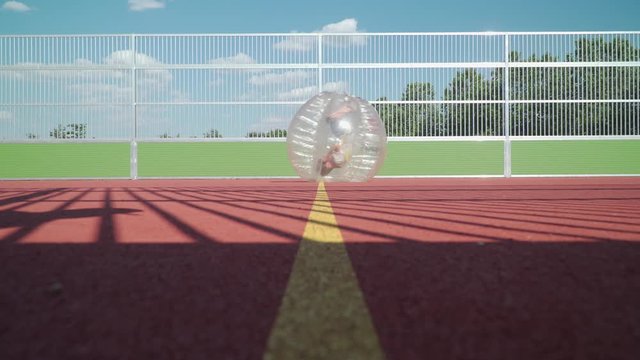 A little kid is rolling through the picture in his bubble during a bubblesoccer match. This shot was filmed with a Sony FS5.