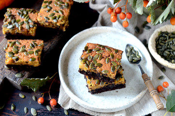 Chocolate pumpkin brownie on a plate on a dark wooden background, still life