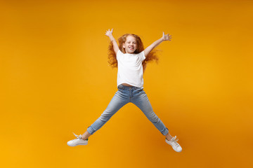 Fototapeta na wymiar Funny little ginger kid girl 12-13 years old in white t-shirt isolated on yellow background. Childhood lifestyle concept. Mock up copy space. Having fun, fooling around, jumping, spreading hands legs.