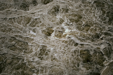 Abstract background, rough water surface. Foaming water, darkness. Foam and bubbles. Stormy waves. Splendor, magnificence and power of nature concept. Foam pattern. Monochrome