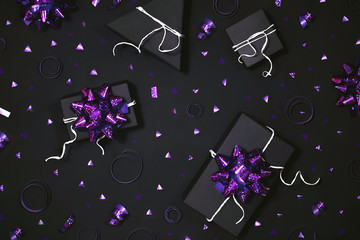 Festive presents on black background with white confetti. New Year gift boxes with purple bows. Wrapped Christmas surprises from above backdrop. Packages and party accessory.