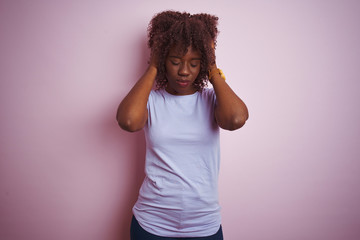 Young african afro woman wearing t-shirt standing over isolated pink background suffering from headache desperate and stressed because pain and migraine. Hands on head.