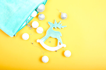 Obraz premium Toy pastel blue deer with Christmas garland and pastel blue cosmetic bag. Flat lay.