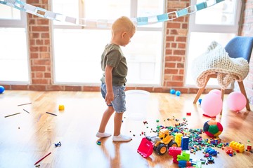 Young caucasian kid playing at kindergarten with toys. Preschooler boy happy at playroom.