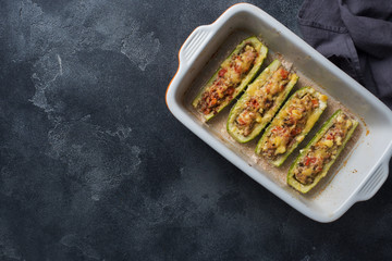 Baked stuffed zucchini boats with minced chicken mushrooms and vegetables with cheese on a baking sheet. Top view Copy space