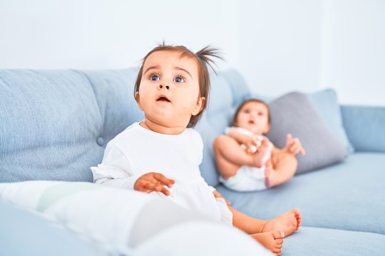 Beautiful infant happy girls playing together at home kindergarten sitting on the sofa