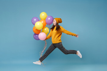 Shocked young woman girl in sweater and hat posing isolated on blue background. Birthday holiday party, people emotions concept. Mock up copy space. Celebrating hold colorful air balloons jumping.