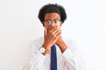 Young african american businessman wearing tie and glasses over isolated white background shocked covering mouth with hands for mistake. Secret concept.