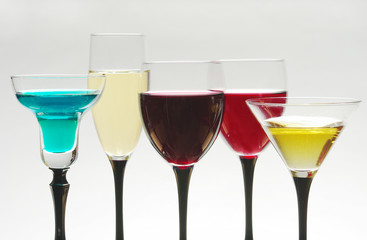 Five colored cocktails in a glass on a white background