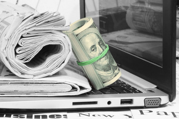 Newspapers, Laptop and Bundle of Money. News Pages with Headlines and Lots of One Hundred Dollar Bills on Computer Keyboard. Business Concept  