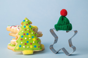 Gingerbread man cookie cutter with knitted hat and cookies isolated on blue. Winter and christmas holiday abstract.