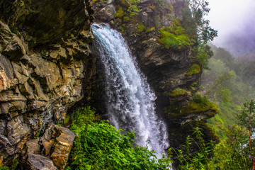 View of the waterfall and rock, you can get inside it by walking along the edge of the rock. Around all the green trees