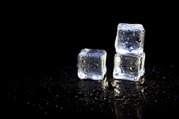 ice cubes reflection on black table background.