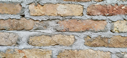 Old fashioned and weathered retro style wall made of stone rock bricks and glued with grey cement with signs of aging