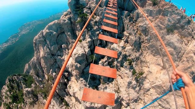 A man with a sense of fear moves on a rope bridge stretched between high rocks.Extreme sport.A test of courage.Adrenaline.