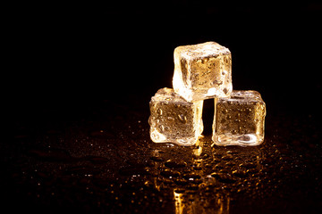 Golden ice cubes on black background.