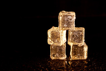 Golden ice cubes on black background.