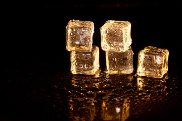 Golden ice cubes on black background.