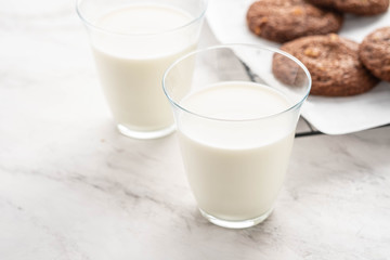 Chocolate cookies on a wire rack with milk on a white background.