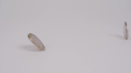 Slow motion close up of a two pound coin hitting a spinning two euro coin and crashing down - Powered by Adobe