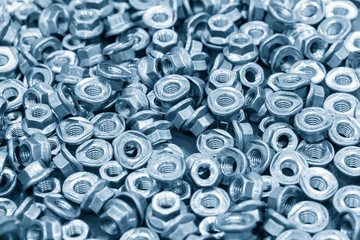The pile of custom hexagon nut for special purpose in the light blue scene.The industrial corrosion free nut and bolt manufacturing concept.