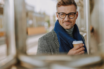 Good-looking gentleman holding takeaway cup of coffee