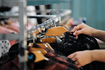 Close-up of the hands of a woman choosing clothes on a hanger in a store.