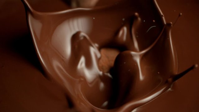 Super slow motion of flying raw chocolate pieces splashing into molten chocolate. Filmed on high speed cinema camera, 1000fps.