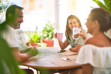 Beautiful family sitting on terrace drinking cup of coffee speaking and smiling