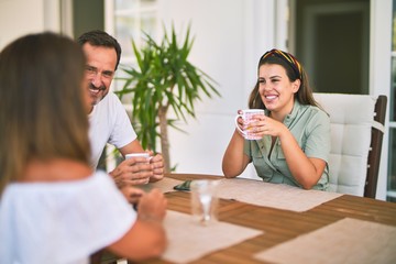 Beautiful family sitting on terrace drinking cup of coffee speaking and smiling
