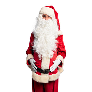 Middle age handsome man wearing Santa Claus costume and beard standing sticking tongue out happy with funny expression. Emotion concept.