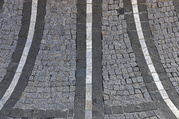 Granite paving stones in the city top view. Stones paved road for horizontal backgrounds and textures. Old granite cobblestone road.
